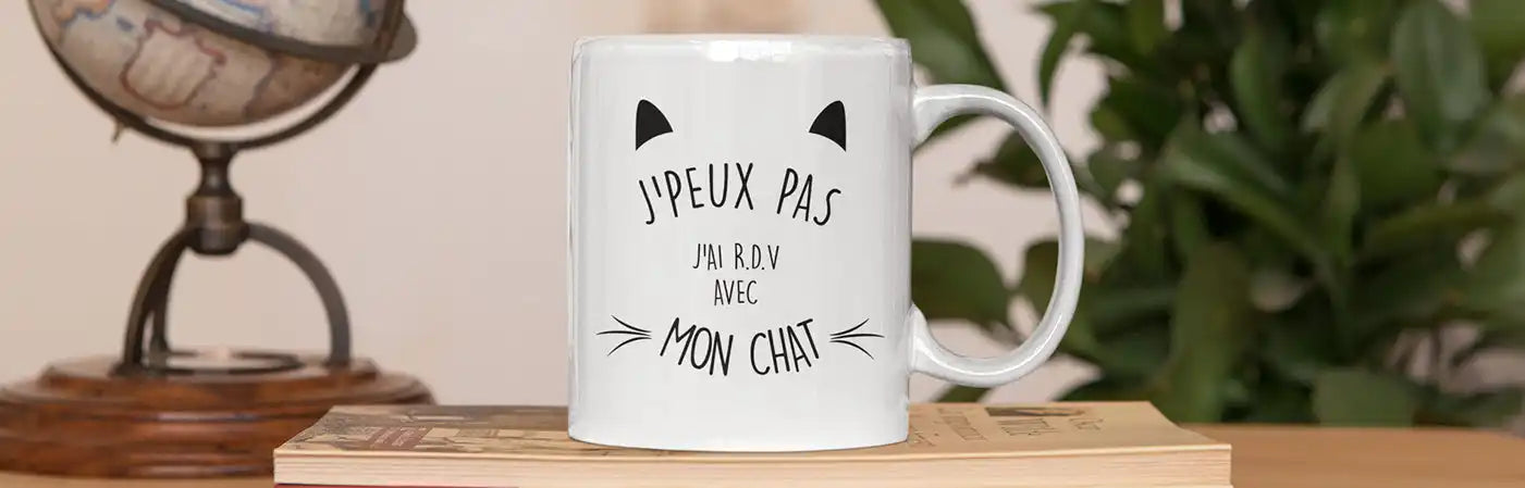 Une tasse en céramique blanche avec un design d'oreilles et de moustaches de chat noir.