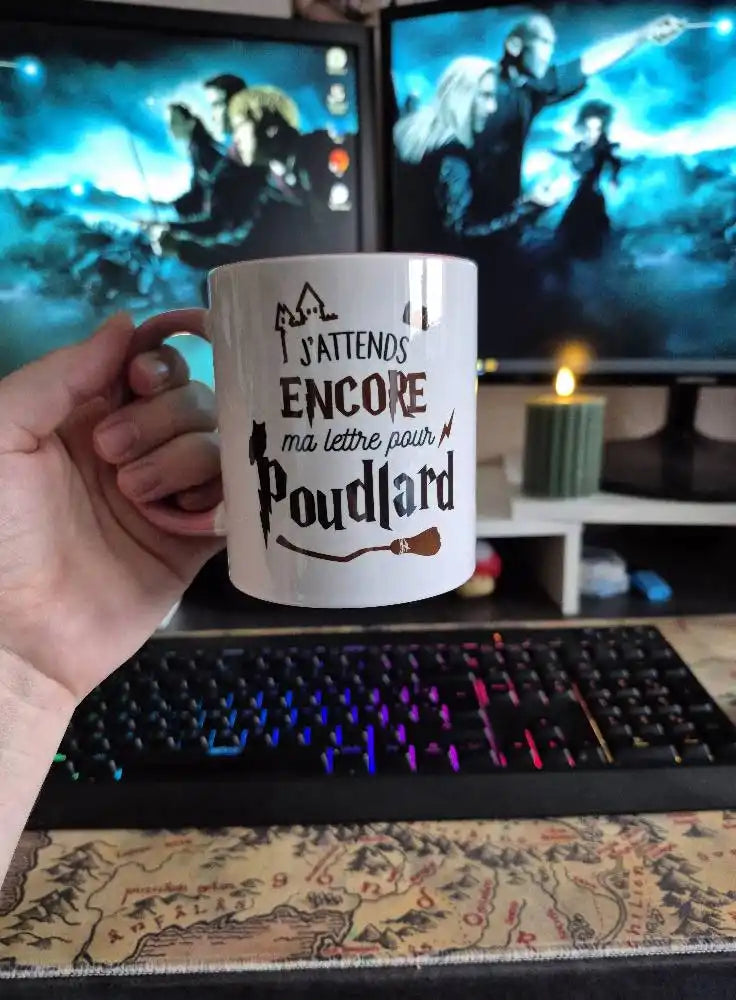 Mug en céramique blanche avec une poignée, présentant une illustration d'un château, d'un chat et d'une baguette magique, et du texte en français.