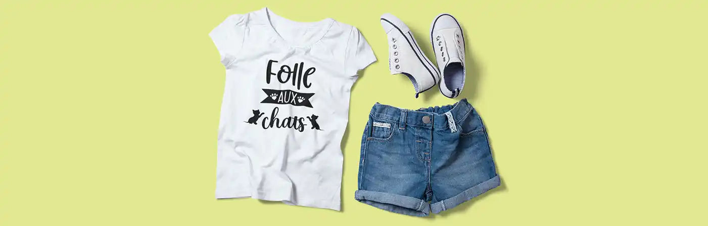 Un t-shirt blanc à manches courtes avec un dessin graphique noir, un short en denim bleu et des chaussures en toile blanches.