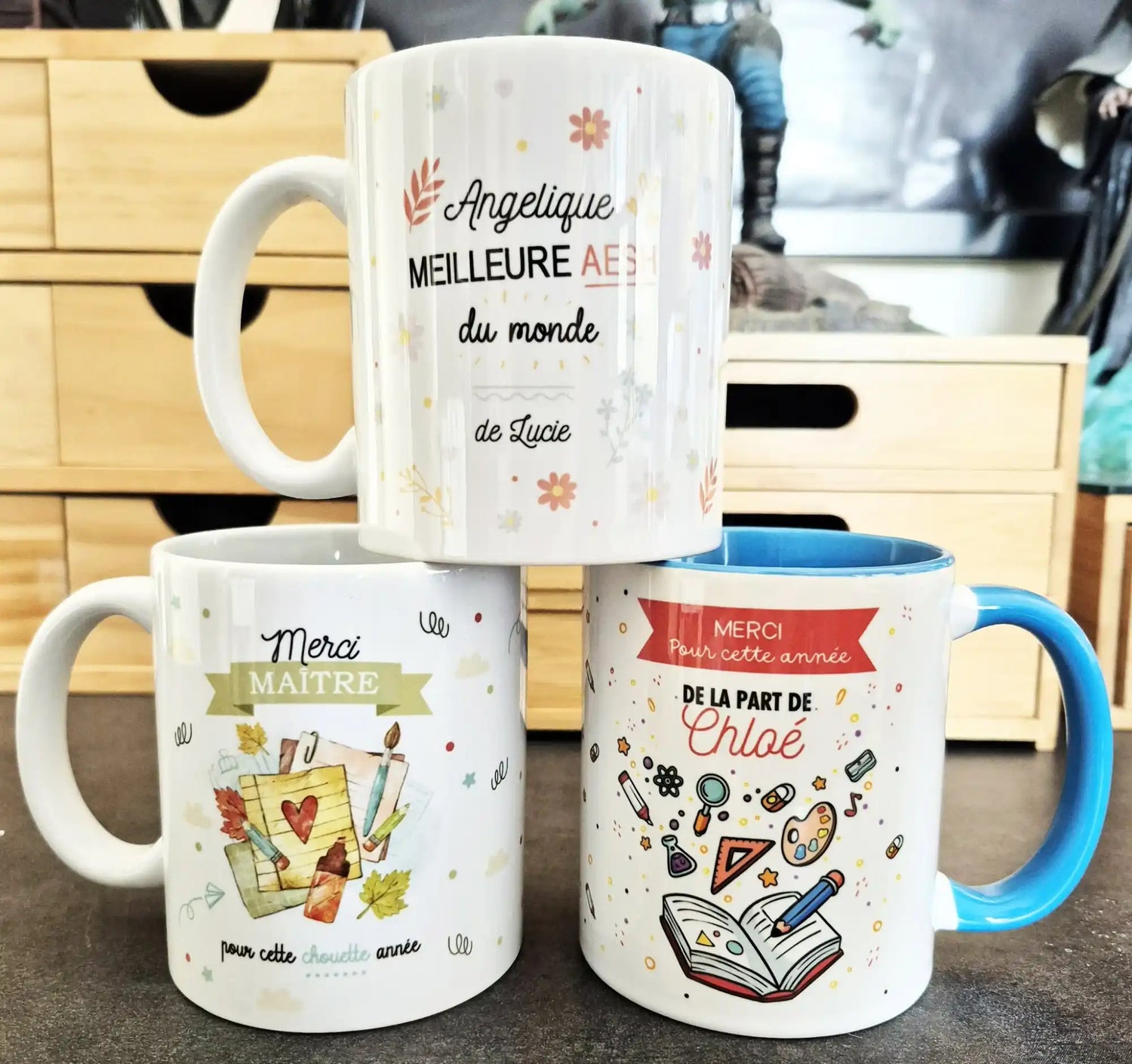 Trois mugs en céramique blanche, chacun avec des motifs colorés uniques.